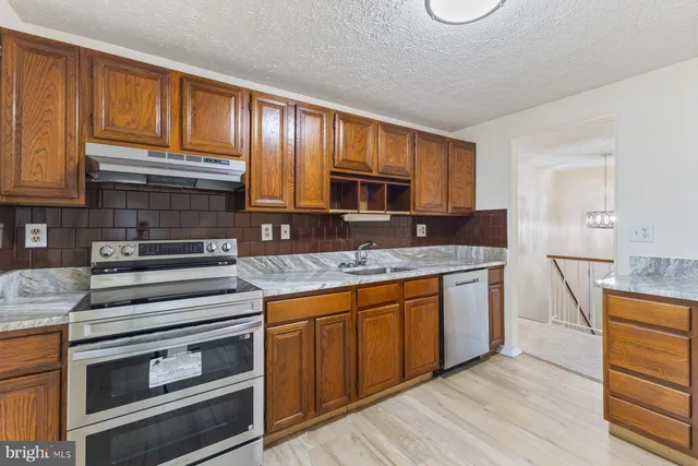 a kitchen with granite countertop wooden cabinets stainless steel appliances and a counter space