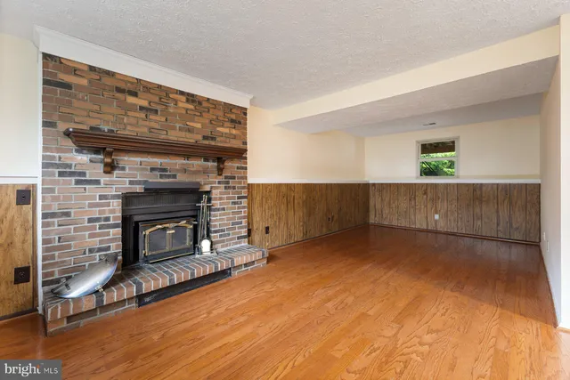 a view of empty room with wooden floor and fireplace