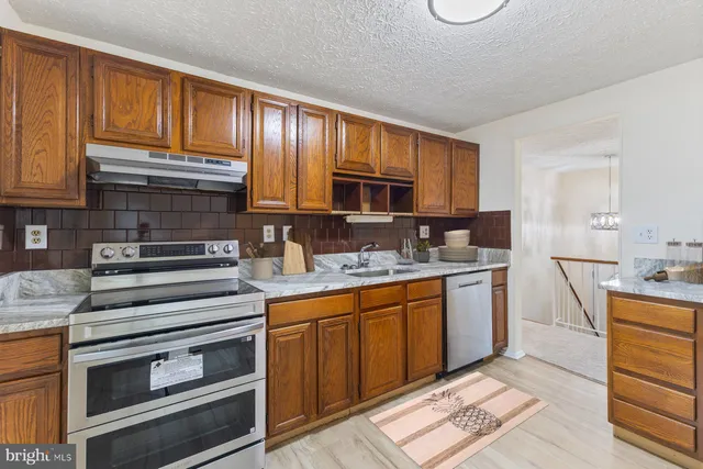a kitchen with granite countertop a sink stove and cabinets