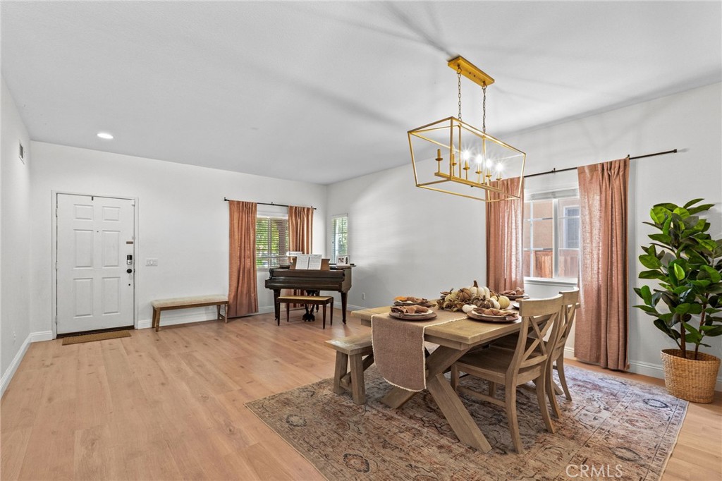 29225 Hydrangea Street Murrieta, CA 92563 - Photo 2 of 38 a dining room with wooden floor a chandelier a wooden table and chairs