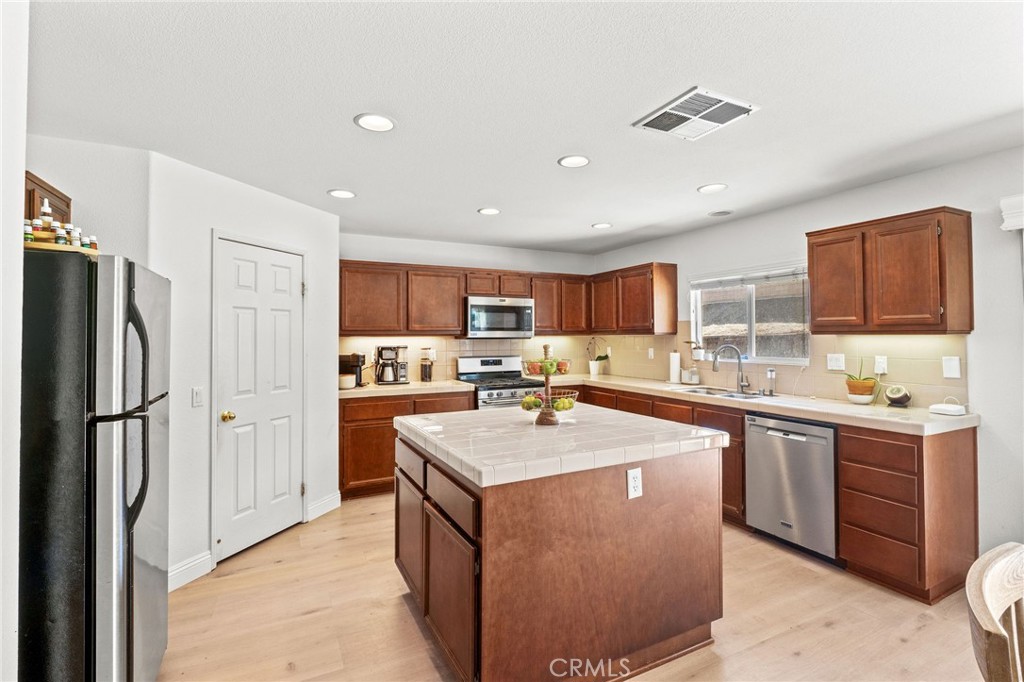29225 Hydrangea Street Murrieta, CA 92563 - Photo 4 of 38 a kitchen with a sink a stove a refrigerator a center island and a window