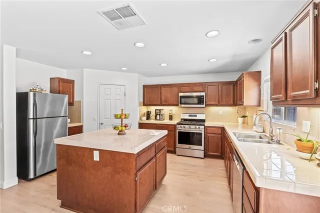 a kitchen with stainless steel appliances granite countertop a refrigerator a sink a stove a microwave and island