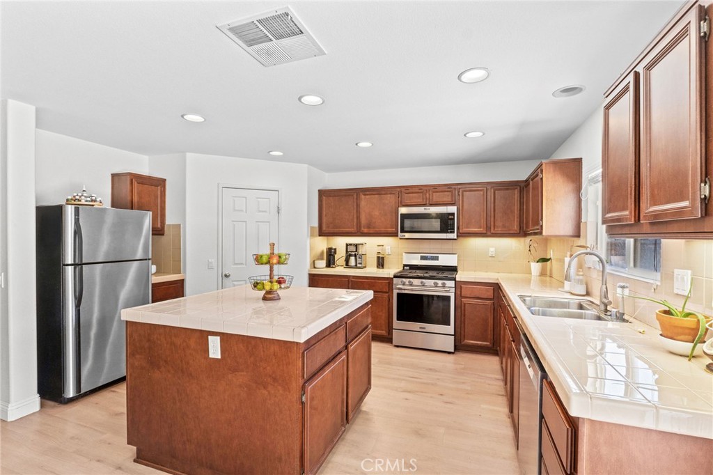 29225 Hydrangea Street Murrieta, CA 92563 - Photo 5 of 38 a kitchen with stainless steel appliances granite countertop a refrigerator a sink a stove a microwave and island