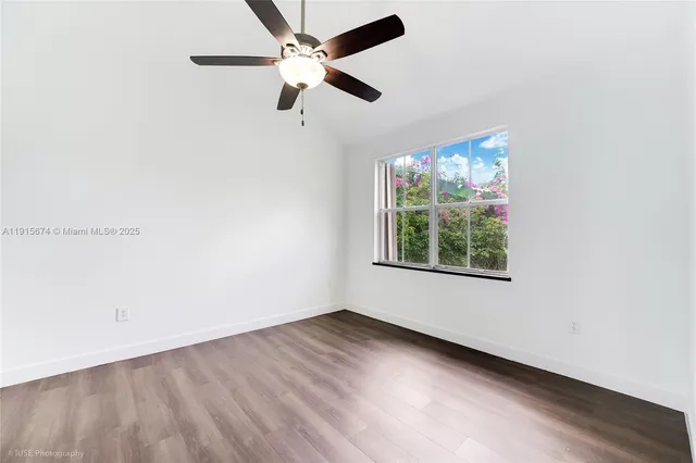 an empty room with wooden floor fan and windows