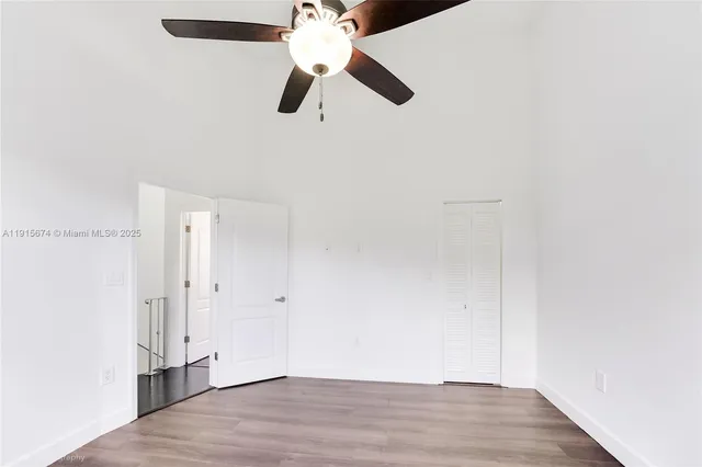 an empty room with wooden floor closet and fan