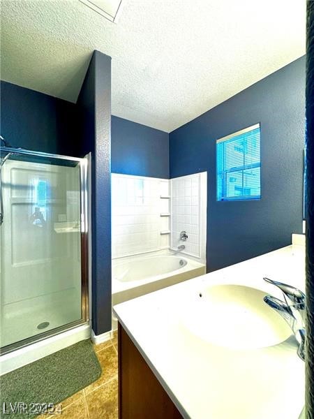 8777 West Maule Avenue, Unit 2103 Las Vegas, NV 89148 - Photo 19 of 33 Full bath with vanity, a textured ceiling, a stall shower, a garden tub, and light tile patterned flooring