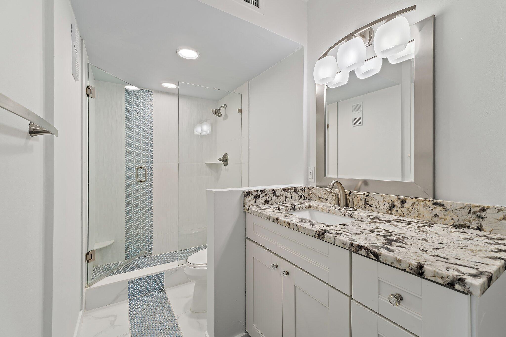 336 Golfview Road, Unit 719 North Palm Beach, FL 33408 - Photo 27 of 72 a bathroom with a granite countertop sink a toilet a shower and a mirror
