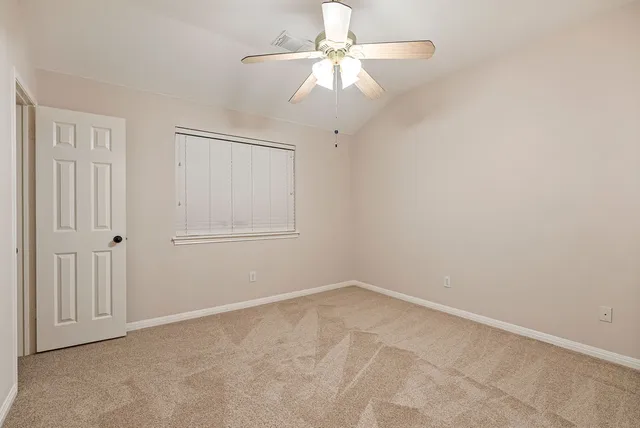 an empty room with a fan & a ceiling fan