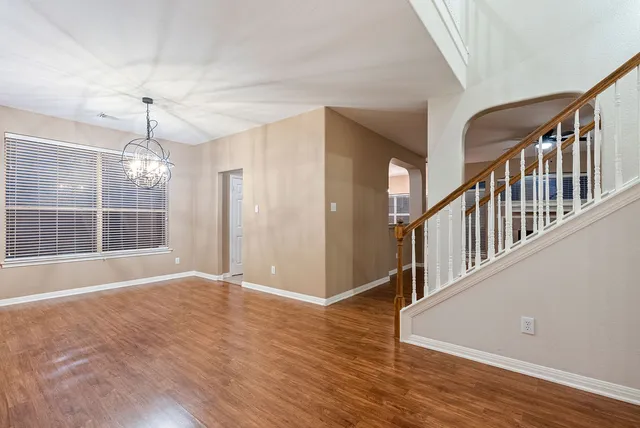 a view of an empty room with wooden floor and windows