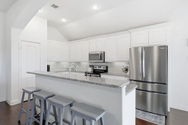 a kitchen with stainless steel appliances granite countertop a refrigerator and a stove top oven