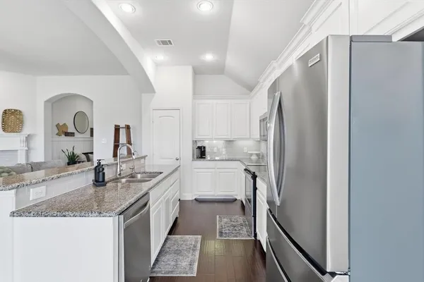 a large white kitchen with granite countertop a sink and stainless steel appliances