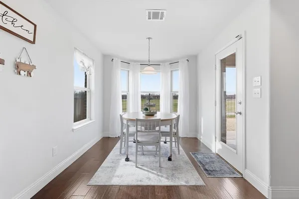 a dining room with wooden floor a chandelier a wooden table and chairs