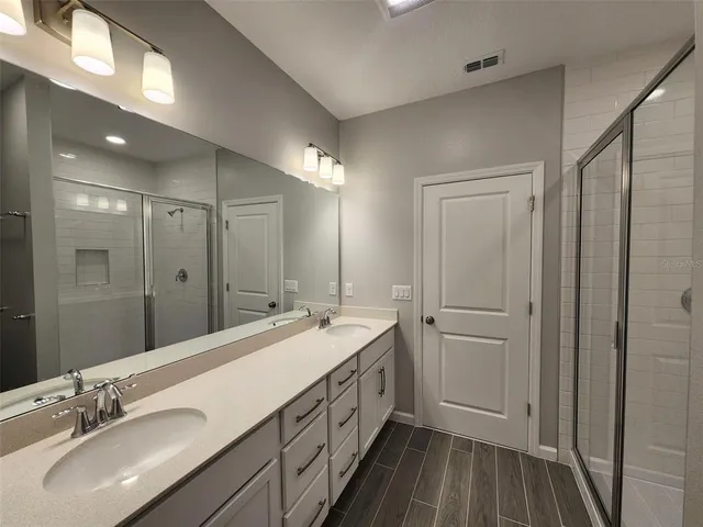 a spacious bathroom with a double vanity sink a mirror and shower