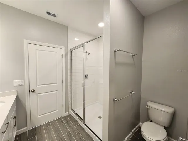 a bathroom with a granite countertop toilet a sink and shower