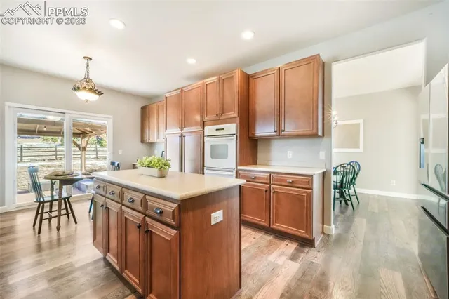 a kitchen with kitchen island granite countertop a stove top oven a sink a dining table and chairs