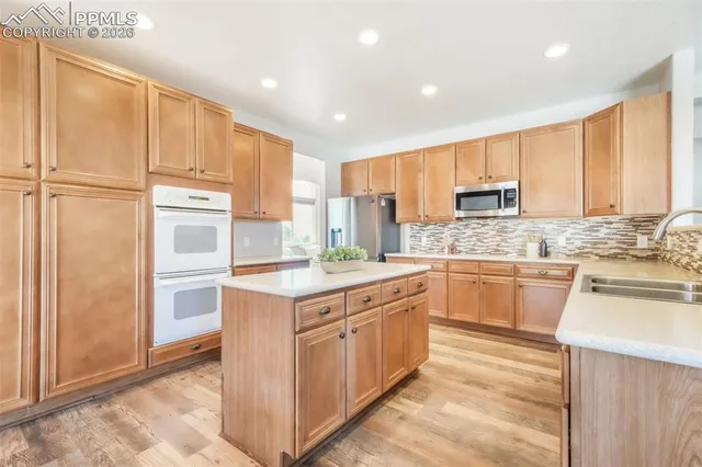 a kitchen with kitchen island granite countertop appliances cabinets and a sink