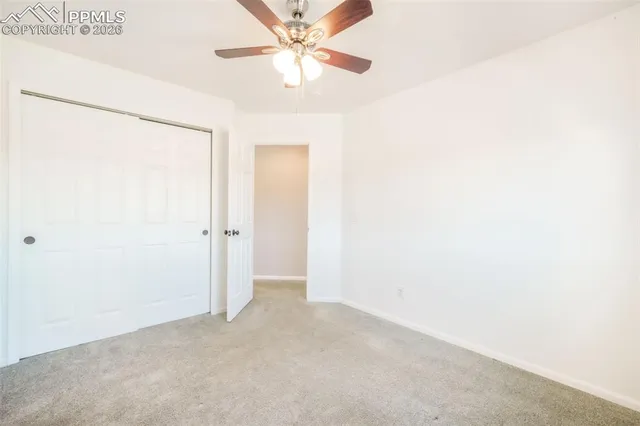 an empty room with closet and fan