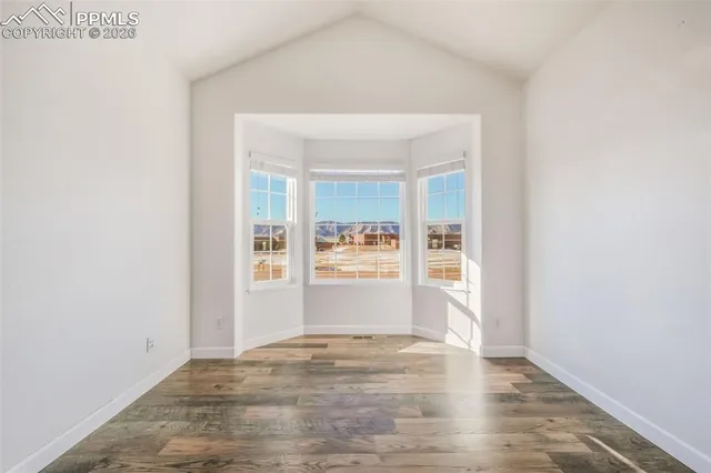 an empty room with wooden floor and window