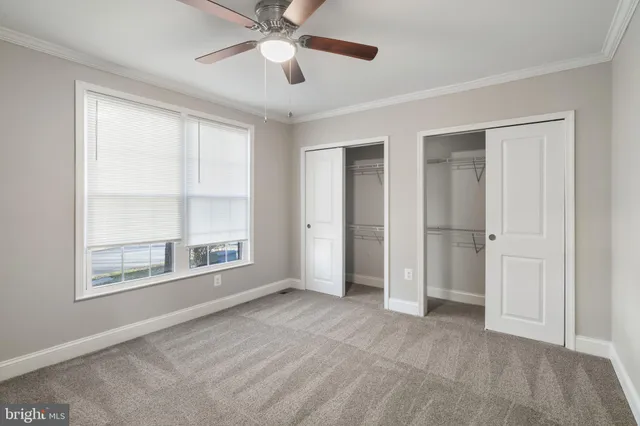 an empty room with chandelier fan and windows