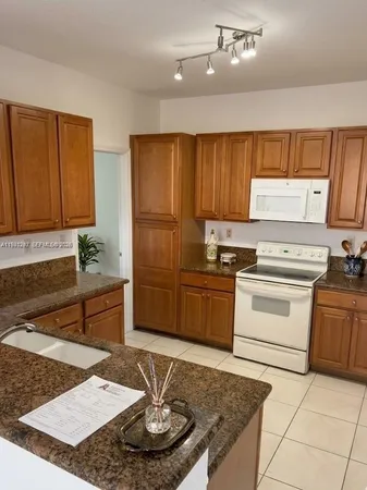 a kitchen with granite countertop wooden cabinets a stove a sink and a refrigerator