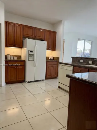 a kitchen with granite countertop a refrigerator stove top oven and sink