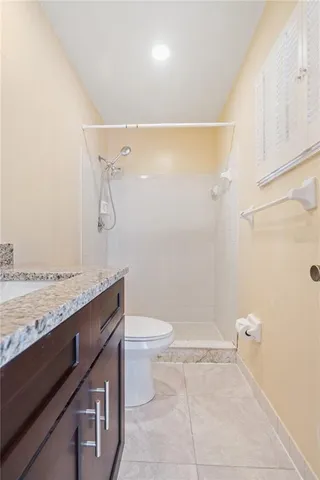 a bathroom with a granite countertop sink a toilet and shower