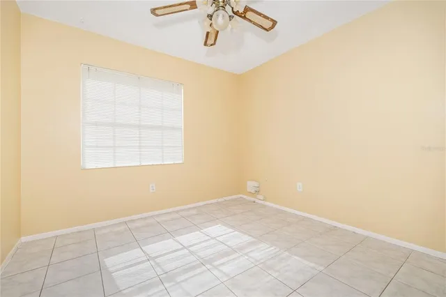 an empty room with a chandelier fan and windows