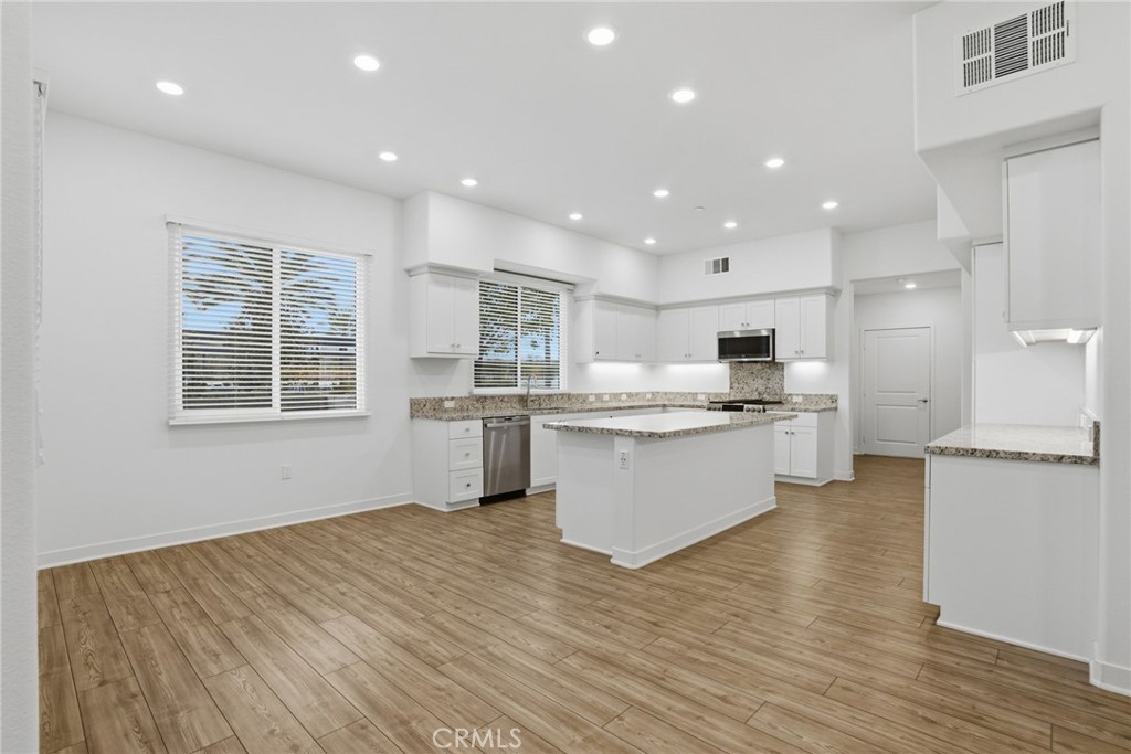 1851 Union Street, Unit 6 Anaheim, CA 92805 - Photo 8 of 26 a large kitchen with kitchen island white cabinets wooden floor and stainless steel appliances