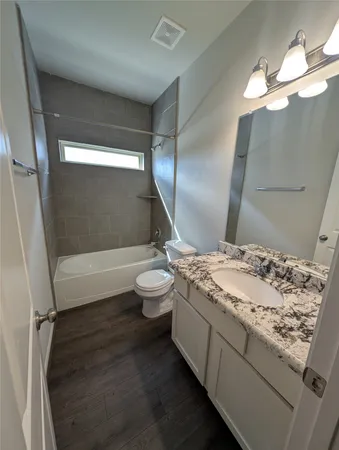 a bathroom with a granite countertop sink a toilet and shower