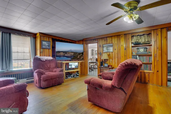 a living room with furniture ceiling fan and a large window