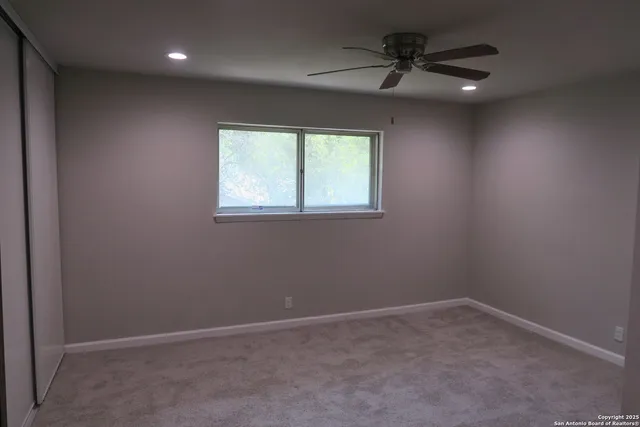 an empty room with a window and a fan