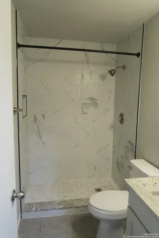 a bathroom with a granite countertop toilet and a shower