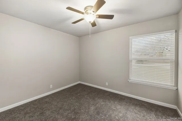 an empty room with a window and a fan