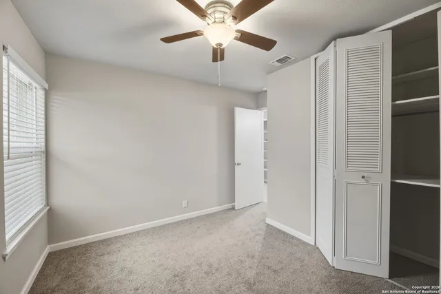 an empty room with a ceiling fan and a window