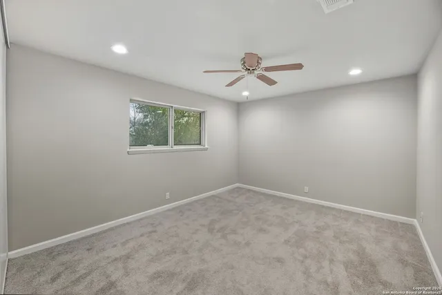 an empty room with a window and a fan