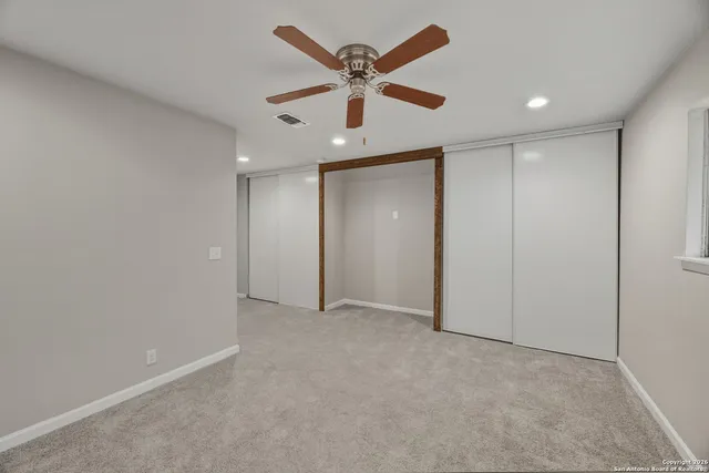 an empty room with ceiling fan and window