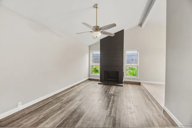a view of an empty room with a window and wooden floor