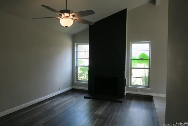 a view of an empty room with wooden floor and a window