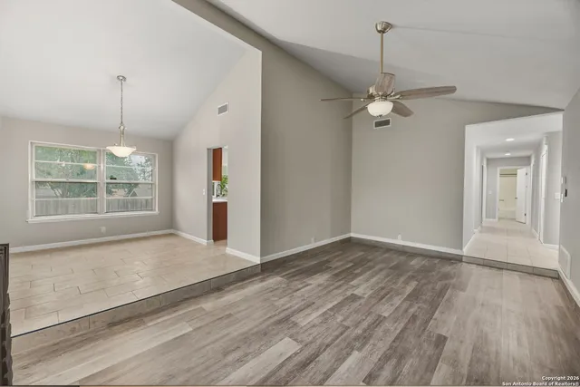 a view of an empty room with a window and wooden floor