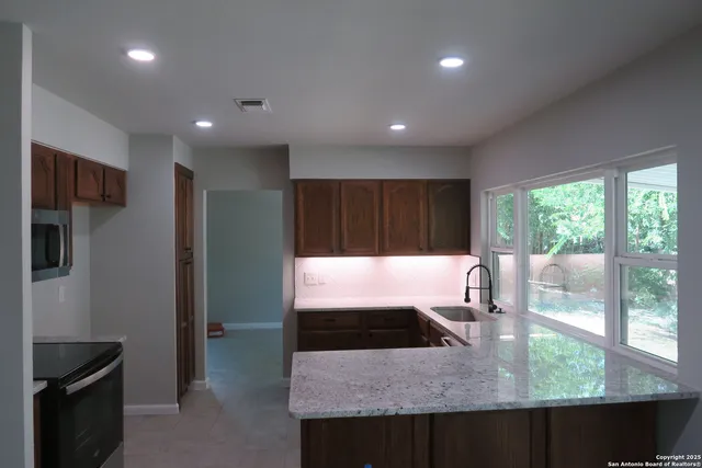 a kitchen with kitchen island a counter top space a sink a refrigerator and a window