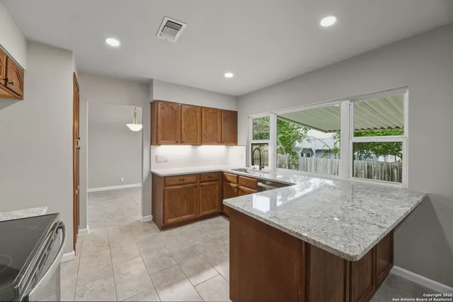 a kitchen with granite countertop a stove a sink and a refrigerator