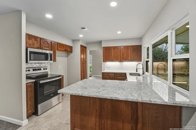 a kitchen with stainless steel appliances granite countertop a stove a sink a microwave a refrigerator and island