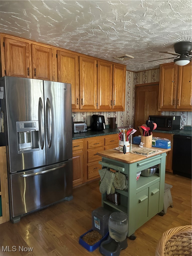 167 Andover Road Woodsfield, OH 43793 - Photo 26 of 50 Kitchen with brown cabinetry, wood finished floors, dishwashing machine, and fridge