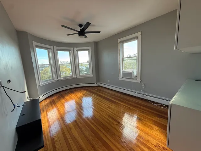 a view of empty room with wooden floor and fan