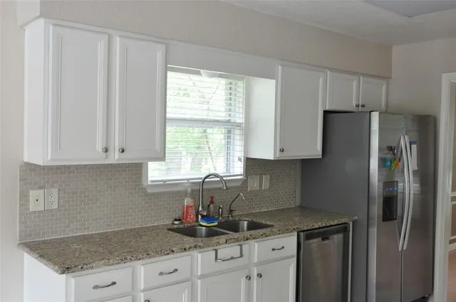 a kitchen with granite countertop a refrigerator sink and cabinets
