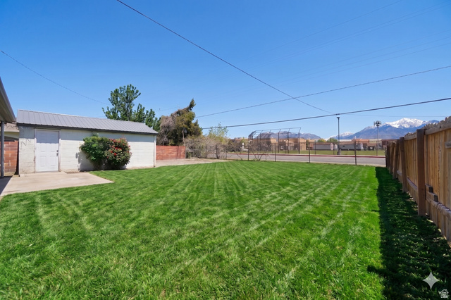 7879 Oak Street Midvale, UT 84047 - Photo 24 of 32 Expansive backyard featuring a manicured lawn, a detached utility building with a metal roof, and a concrete patio