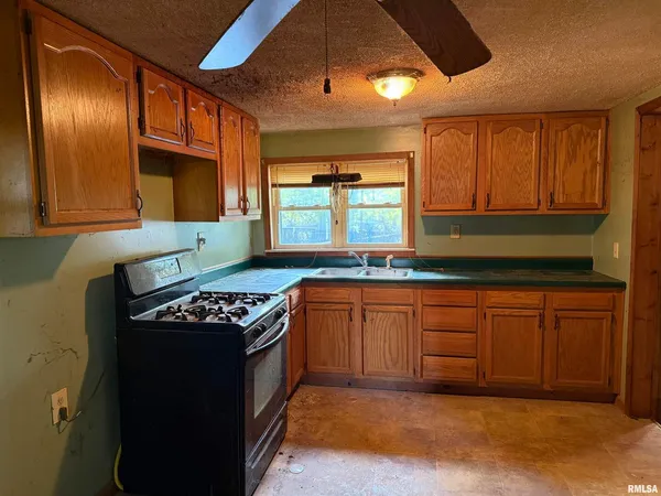 a kitchen with granite countertop stainless steel appliances sink stove and cabinets