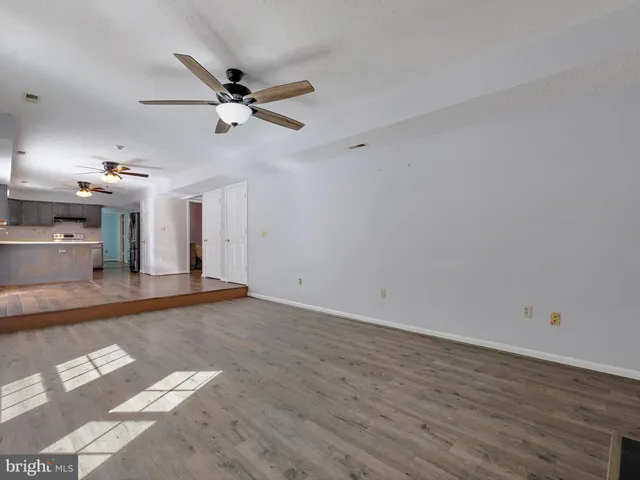 an empty room with wooden floor ceiling fan and windows