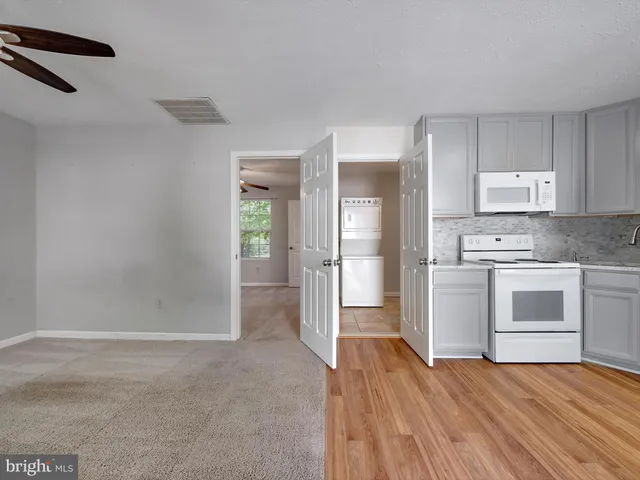 a view of a kitchen with white cabinets and stainless steel appliances