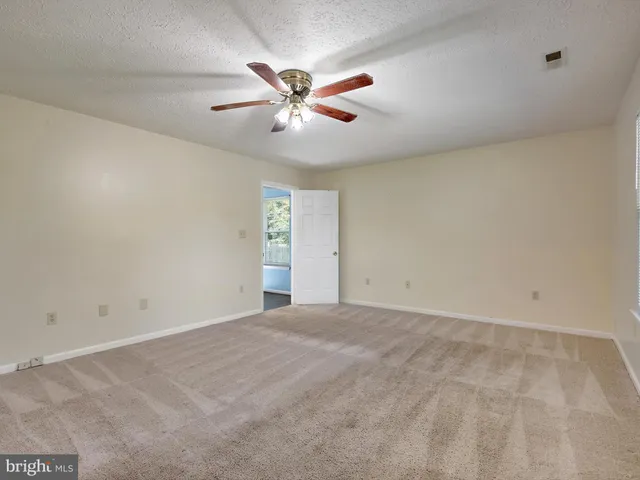 an empty room with windows and fan